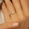 Bague en or 18 carats en forme de cœur ornée d'un diamant central et de petites pierres brillantes entourant la pierre principale, idéale pour une demande en mariage ou un cadeau spécial, mettant en valeur l'élégance et la sophistication des bijoux modernes