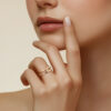 Bague en or avec un design élégant, mise en valeur par une main délicate. La main d'une femme touche doucement son visage, accentuant la beauté et la sophistication de la bague. Parfaite pour des occasions spéciales ou comme bijou quotidien, cette bague est un symbole de style intemporel. Modèle : Diamant.