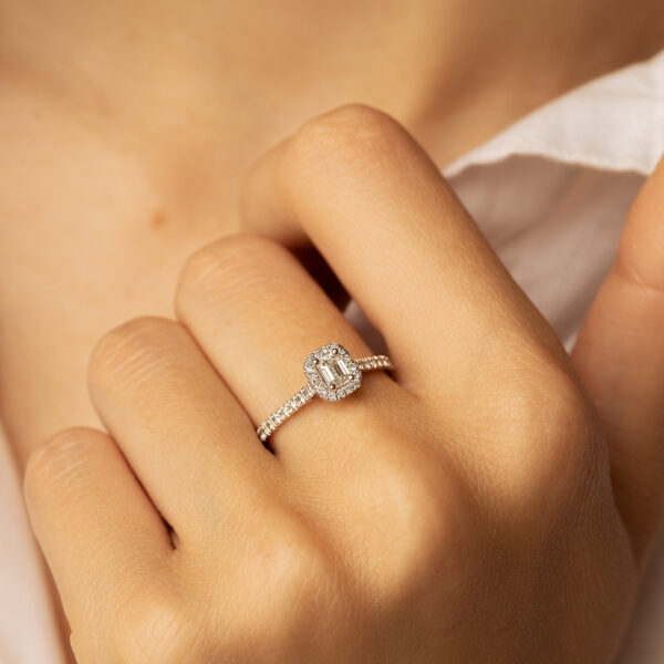 Bague en diamant avec une taille émeraude, ornée de pierres précieuses et monture en or, mettant en valeur un style élégant et raffiné, parfaite pour une demande en mariage ou une occasion spéciale.