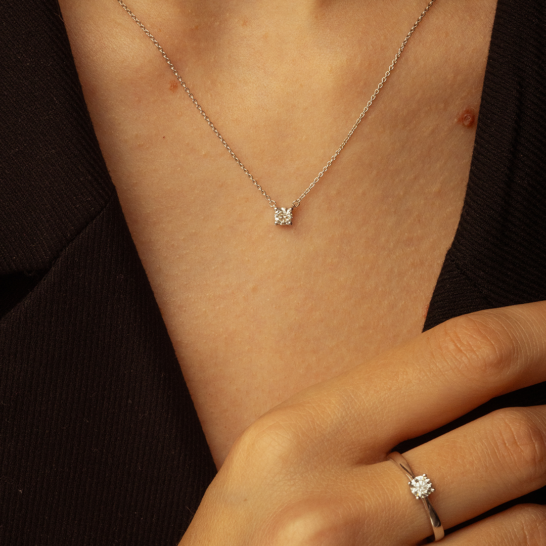 Collier en diamant et bague en diamant, mettant en avant un pendentif carré scintillant et un anneau délicat, porté par une femme, style moderne et élégant, idéal pour des occasions spéciales ou un usage quotidien, bijou en argent avec pierres précieuses.