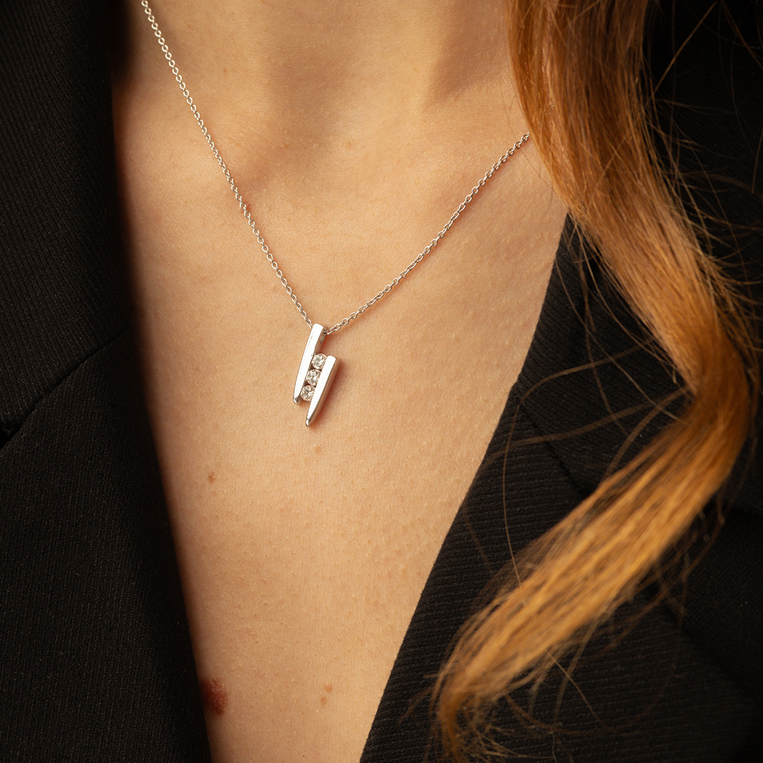 Collier élégant en argent avec pendentif en forme de V, incrusté de diamants, porté par une personne avec des cheveux roux, mettant en valeur la mode moderne et les bijoux raffinés.