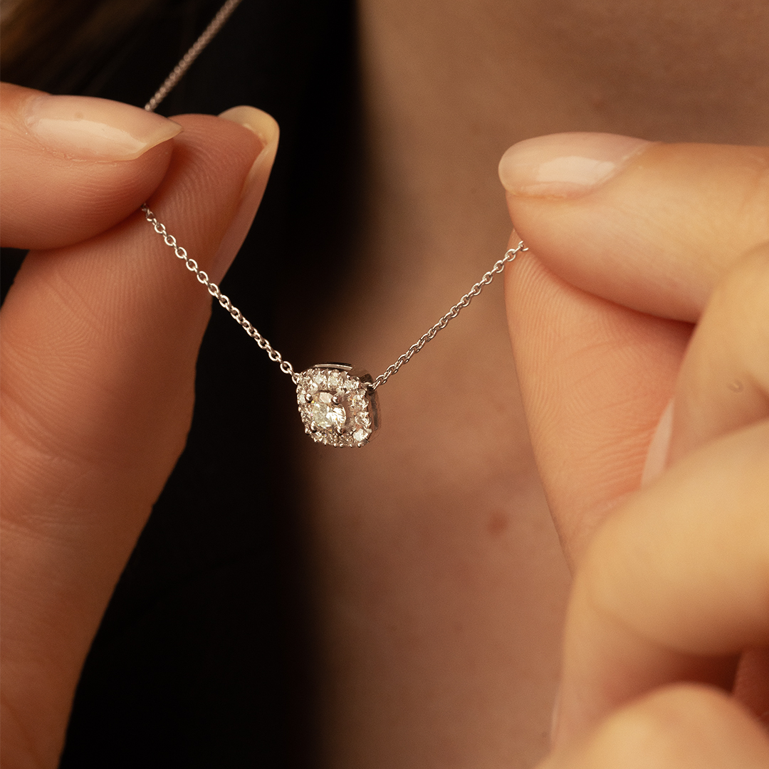 Collier en argent avec un pendentif en diamant, mettant en valeur une pièce joaillière élégante avec plusieurs diamants scintillants, parfait pour des occasions spéciales, porté par une femme qui tient délicatement le bijou, ajoutant une touche de sophistication et de luxe.