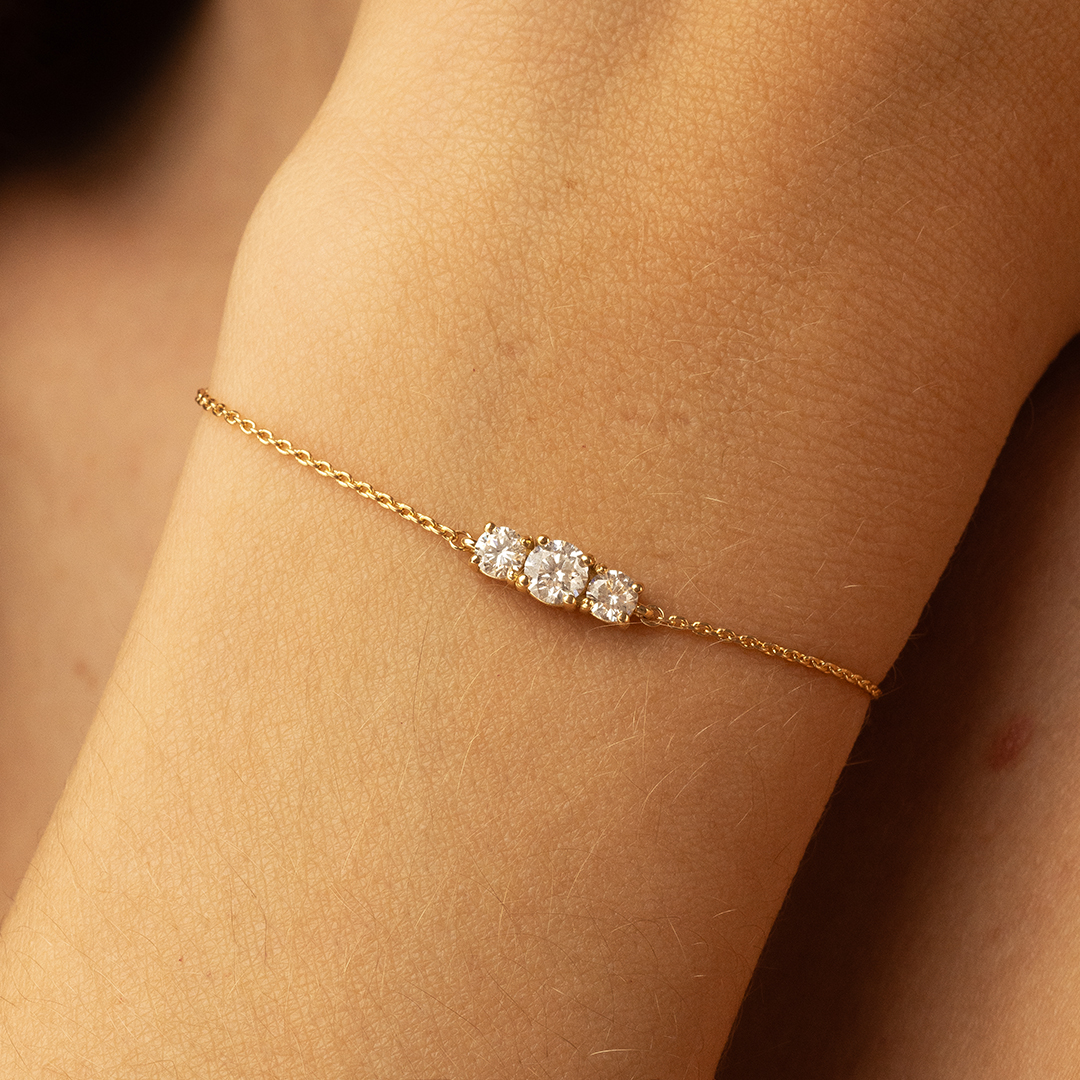 Bracelet délicat en or avec trois diamants scintillants, posant élégamment sur une peau douce. Ce bijou minimaliste est idéal pour les occasions spéciales ou pour ajouter une touche de luxe à votre tenue quotidienne. Parfait pour les amateurs de bijoux raffinés. Modèle + diamant.