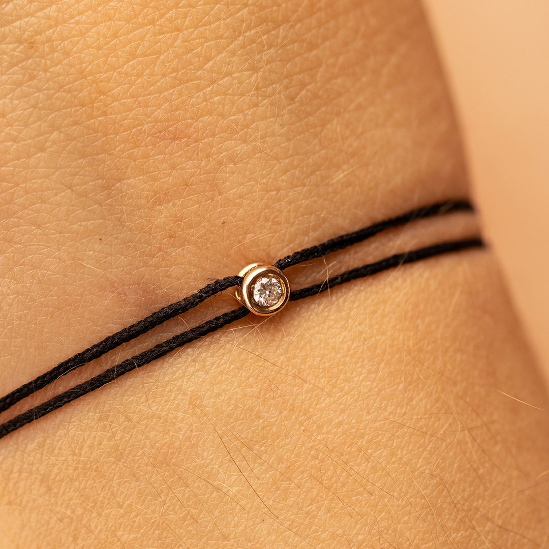 Bracelet délicat en cordon noir avec un pendentif en or et un diamant brillant. Ce bijou minimaliste est parfait pour une tenue élégante, combinant la simplicité du cordon avec l'éclat du diamant. Modèle chic avec diamant, idéal pour les amateurs de joaillerie raffinée.