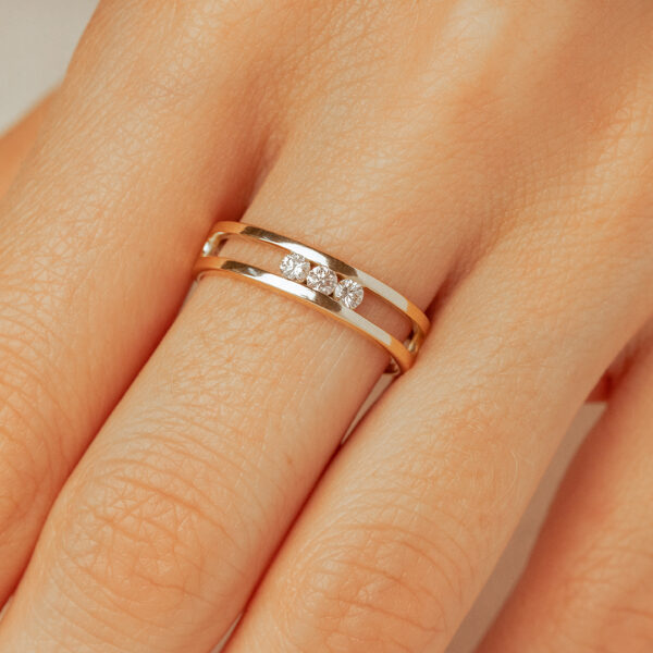 Bague en or et argent avec trois diamants, design élégant et moderne, portée sur une main, idéale pour les fiançailles ou les occasions spéciales, mettant en valeur un style contemporain et raffiné, modèle + diamant