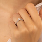 Bague en diamant et or blanc modèle élégant avec un diamant central, portée sur une main délicate, mettant en valeur la brillance des pierres et le design raffiné, idéale pour des occasions spéciales et des fiançailles.