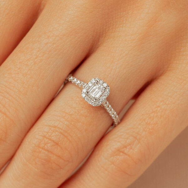 Bague en diamant avec une taille émeraude, ornée de petits diamants en pavé sur un raffinement délicat, mise en avant sur un doigt, parfaite pour les fiançailles ou comme symbole d'amour éternel, modèle intemporel et élégant.