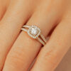 Bague de fiançailles élégante en or jaune ornée d'un diamant central rond entouré de petits diamants, avec un design délicat à double bande, parfaite pour symboliser l'amour et l'engagement.