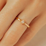 Bague en or avec un diamant scintillant, délicatement posée sur un doigt, mettant en valeur le design minimaliste et élégant. Parfaite pour les fiançailles ou les occasions spéciales, cette bague est un intemporel qui symbolise l'amour et l'engagement.