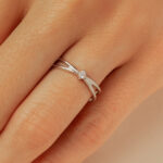 Bague en argent avec un design élégant et moderne, ornée d'un diamant central. La bague présente des courbes délicatement travaillées, représentant l'amour et l'engagement. Idéale pour une demande en mariage ou une occasion spéciale. Modèle raffiné + diamant.