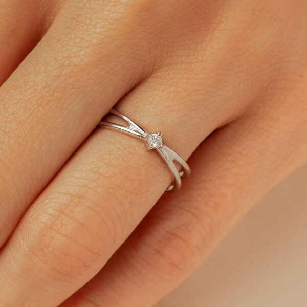 Bague en argent avec un design élégant et moderne, ornée d'un diamant central. La bague présente des courbes délicatement travaillées, représentant l'amour et l'engagement. Idéale pour une demande en mariage ou une occasion spéciale. Modèle raffiné + diamant.