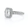 Bague en diamants avec un coussin central en forme d'émeraude, entourée de petits diamants scintillants, la monture est en or blanc, idéale pour une demande en mariage ou une occasion spéciale. Cette bague combine élégance et luxe, mettant en valeur des pierres précieuses de haute qualité dans un design raffiné.