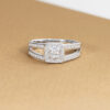 Bague en diamant ouverte avec un design moderne, présentant une pierre centrale carré entourée de multiples petites pierres précieuses. Idéale comme bague de fiançailles ou bijou de luxe, avec un éclat remarquable, ajoutant une touche d'élégance à toute collection de bijoux.