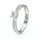 Bague de fiançailles en or blanc, ornée d'un diamant brillant en taille ronde, avec des petits diamants sertis sur les côtés, idéale pour les demandes en mariage, ajoutant une touche d'élégance et de romantisme à chaque occasion.