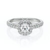 Bague de fiançailles élégante en or blanc ornée d'un diamant central de style vintage, entouré d'un halo de diamants plus petits sur l'anneau et sur les côtés, offrant une brillance exceptionnelle. Parfaite pour une proposition romantique ou un cadeau raffiné, associant sophistication et glamour.