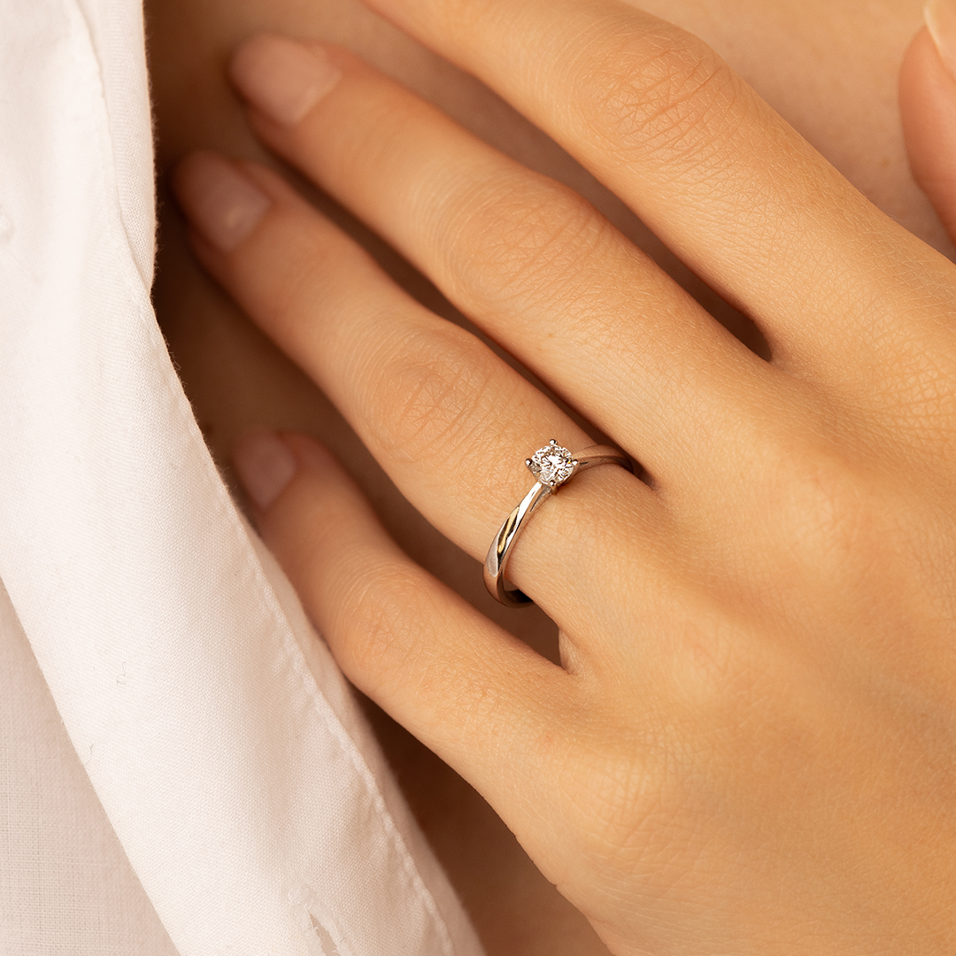 Bague en or avec un diamant, modèle élégant et moderne, portée sur une main délicate. Idéale pour les fiançailles ou comme bijou moderne, mettant en valeur la brillance du diamant sur une monture raffinée.