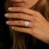 Bague en diamant octogonale au design élégant, mettant en valeur un brillant central en taille émeraude entouré de petits diamants scintillants, portée sur un doigt d'une main délicate. Idéale pour les fiançailles ou comme bijou de luxe, cette bague est un choix parfait pour les amateurs de joaillerie raffinée.
