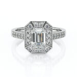 Bague en diamant en or blanc avec une pierre centrale émeraude entourée de petits diamants brillants, présentant un design élégant et moderne, idéale pour une demande en mariage ou une occasion spéciale.