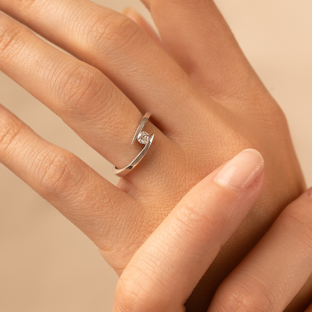Bague en argent moderne avec un diamant, portée sur un doigt. Design minimaliste et élégant, mettant en valeur la brillance de la pierre précieuse. Parfaite pour un usage quotidien ou une occasion spéciale, cette bague allie chic et sophistication. Idéale comme bijou de mode ou pour un cadeau mémorable.