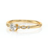 Bague de fiançailles en or jaune avec un diamant central brillant entouré de petits diamants sur les côtés, design élégant et moderne, symbole d'amour éternel, parfaite pour un engagement ou une occasion spéciale.