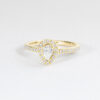 Bague en or jaune avec un diamant en forme de poire centrale entouré de petites pierres précieuses, idéale pour les fiançailles ou les occasions spéciales, combines élégance et brillance.