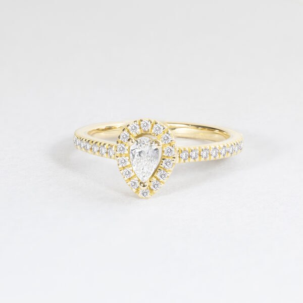 Bague en or jaune avec un diamant en forme de poire centrale entouré de petites pierres précieuses, idéale pour les fiançailles ou les occasions spéciales, combines élégance et brillance.