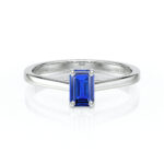Bague en or blanc avec une taille émeraude de saphir bleu, design élégant, sertie de quatre griffes pour un maintien optimal. Parfaite pour les fiançailles ou comme bijou de luxe, cette bague met en valeur la beauté du saphir tout en offrant un éclat moderne.