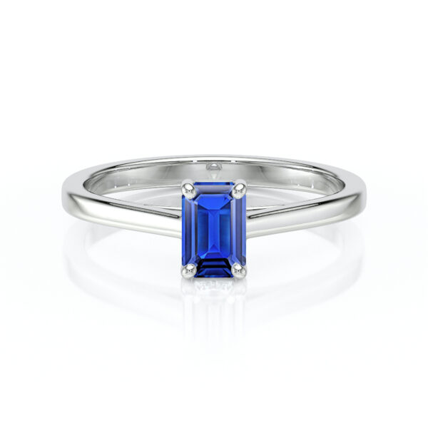 Bague en or blanc avec une taille émeraude de saphir bleu, design élégant, sertie de quatre griffes pour un maintien optimal. Parfaite pour les fiançailles ou comme bijou de luxe, cette bague met en valeur la beauté du saphir tout en offrant un éclat moderne.