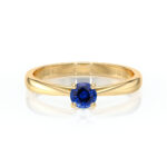 Bague en or jaune avec un saphir bleu rond en solitaire, mise en valeur par un design élégant et moderne. Idéale pour une proposition de mariage ou un cadeau spécial. Cette bague allie qualité et esthétique, mettant en avant la beauté du saphir et la brillance de l'or.