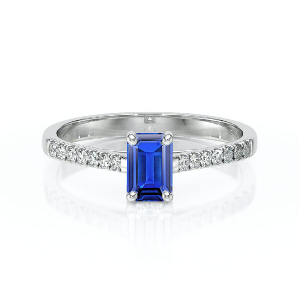 Bague en or blanc sertie d'une pierre précieuse saphir bleu de taille émeraude, entourée de diamants brillants sur chaque côté, parfaite pour une demande en mariage ou une occasion spéciale, modèle élégant et intemporel, mettant en valeur la beauté et l'éclat du saphir.