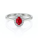 Bague en or blanc avec un saphir rouge central oval entouré de diamants scintillants. Idéale pour les fiançailles ou les occasions spéciales, cette bague de design élégant et intemporel met en valeur le contraste entre le rouge vibrant du saphir et l'éclat des diamants. Modèle + diamant.