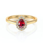 Bague en or avec une pierre précieuse rouge en forme de poire, entourée de diamants, symbolisant l'amour et l'élégance, idéale pour une demande en mariage ou une occasion spéciale.