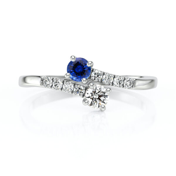 Bague en or blanc ornée d'un saphir bleu rond et d'un diamant central brillant, avec des diamants en ligne sur le corps de la bague, symbole d'élégance et de sophistication. Parfait pour une demande en mariage ou une occasion spéciale, ce modèle de bague allie modernité et classicisme.