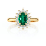 Bague en or avec une pierre précieuse verte ovale entourée de diamants scintillants, offrant un design élégant et raffiné, parfaite pour des occasions spéciales ou comme bague de fiançailles.