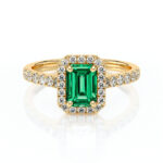 Bague en or avec un diamant émeraude au centre, entourée de petits diamants scintillants, modèle élégant et luxueux, idéale pour des occasions spéciales comme les fiançailles ou les anniversaires, mettant en avant une gemme de couleur verte vibrante qui attire le regard.