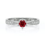 Bague en argent avec un rubis rond central et des diamants sur les côtés, modèle élégant et moderne, idéale comme bague de fiançailles ou bijou de luxe pour une occasion spéciale.