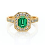 Bague en or avec une pierre précieuse émeraude à coupe émeraude entourée de diamants brillants, design vintage chic, idéale pour les fiançailles ou en tant que bijou de luxe, mettant en valeur l'élégance et le raffinement.