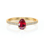 Bague en or avec un rubis en forme de poire au centre entouré de diamants, idéale pour une proposition de mariage ou un cadeau spécial, offrant un éclat raffiné et une touche d'élégance.