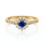 Bague en or élégante avec une pierre précieuse bleu en forme de fleur, entourée de diamants scintillants. Idéale pour les fiançailles ou comme bijou de luxe, cette bague en or combine sophistication et éclat, illustrant un design intemporel et romantique.
