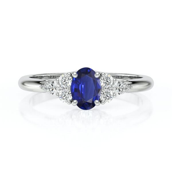 Bague en or blanc ornée d'un saphir oval bleu au centre, entouré de trois diamants brillants, idéale pour une proposition de mariage ou une occasion spéciale. Bague de fiançailles élégante avec un design moderne, mettant en valeur la beauté du saphir et l'éclat des diamants, parfaite pour les amateurs de bijoux raffinés.