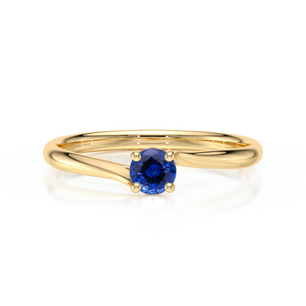 Bague en or avec un design élégant et moderne, mettant en valeur un saphir bleu taille ronde au centre, entouré de griffes dorées. Idéale pour une proposition de mariage ou un cadeau spécial, ajoutant une touche de luxe et d'originalité à toute collection de bijoux.