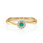 Bague en or jaune élégante, ornée d'un centre en émeraude éclatante, entourée de diamants scintillants, offrant un design raffiné et moderne, parfaite pour une occasion spéciale ou comme symbole d'amour. Idéale pour les amateurs de bijoux de luxe et de pièces uniques.