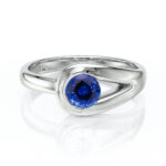Bague en argent avec un design moderne, ornée d'un diamant bleu brillant, idéale pour des occasions spéciales ou comme bijou de tous les jours. Le style élégant de cette bague met en valeur le gemme bleu, créant une combinaison parfaite entre sophistication et beauté contemporaine.