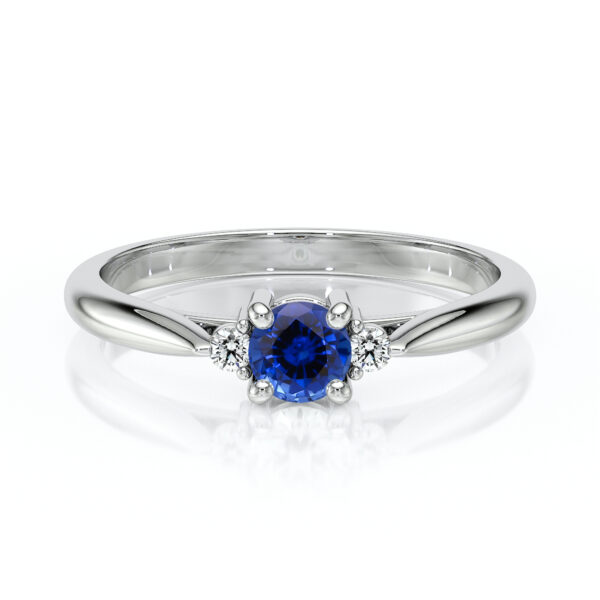 Bague en or blanc avec un saphir bleu central entouré de diamants, illustrant l'élégance et le luxe, parfait pour des fiançailles ou une occasion spéciale.