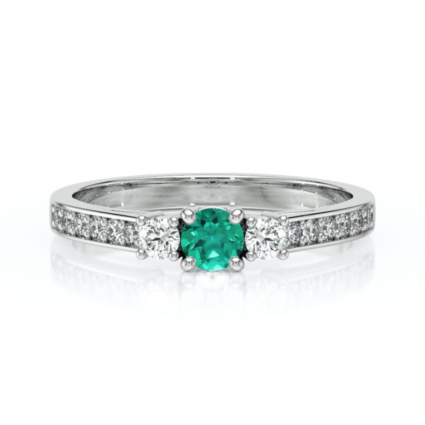 Bague en or blanc avec une pierre précieuse centrale en émeraude, entourée de deux diamants, ornée d'une bande de diamants sur le côté, idéale pour une occasion spéciale ou comme bague de fiançailles, mettant en avant le contraste entre l'émeraude verte lumineuse et les diamants scintillants, ajoutant une touche d'élégance et de sophistication.