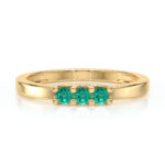 Bague en or avec trois pierres précieuses vertes, modèle élégant et moderne, mettant en avant des gemmes scintillantes entourées d'une monture dorée, idéale comme bijoux de mode ou d'occasion spéciale.