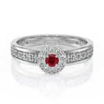 Bague en or blanc avec un magnifique rubis central entouré de diamants étincelants, idéal pour une proposition de mariage ou une occasion spéciale. Design élégant et contemporain, mettant en valeur le contraste entre la couleur rouge du rubis et l'éclat des pierres précieuses, parfaite pour les amateurs de bijoux raffinés.