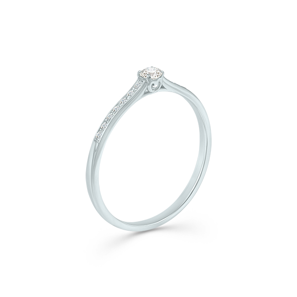 Bague de fiançailles délicate en or blanc avec un diamant central, caractérisée par un design élégant et moderne. La monture présente un magnifique scintillement grâce à des petites pierres précieuses incrustées sur le côté. Idéale pour une demande en mariage, cette bague allie artisanat de qualité et sophistication.