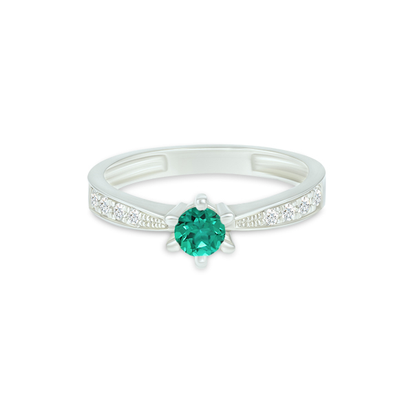 Bague élégante en argent avec une pierre précieuse verte en forme de rond au centre, entourée de petits diamants scintillants sur les côtés. Cette création raffinée représente un modèle de bijou parfait pour les fiançailles ou les occasions spéciales.