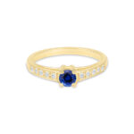 Bague en or jaune avec un magnifique saphir bleu au centre, entouré de diamants scintillants sur les côtés, symbole d'élégance et de raffinement. Idéale comme bague de fiançailles ou bijou de mariage, mêlant modernité et tradition avec le diamant et la pierre précieuse.